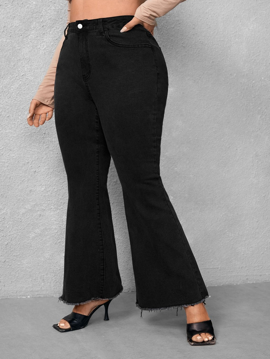 Black flared jeans worn by a person on a gray background