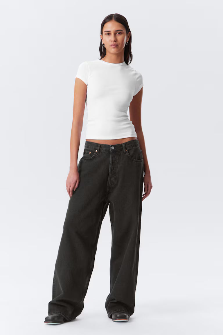 Woman wearing a white top and black jeans on a white background