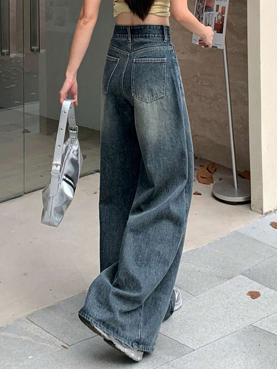 Person wearing wide-leg jeans holding a bag on a sidewalk.
