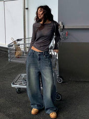 Person wearing a dark long-sleeve top and blue jeans standing in front of a shopping cart.
