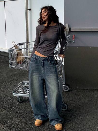 Person wearing a dark long-sleeve top and blue jeans standing in front of a shopping cart.