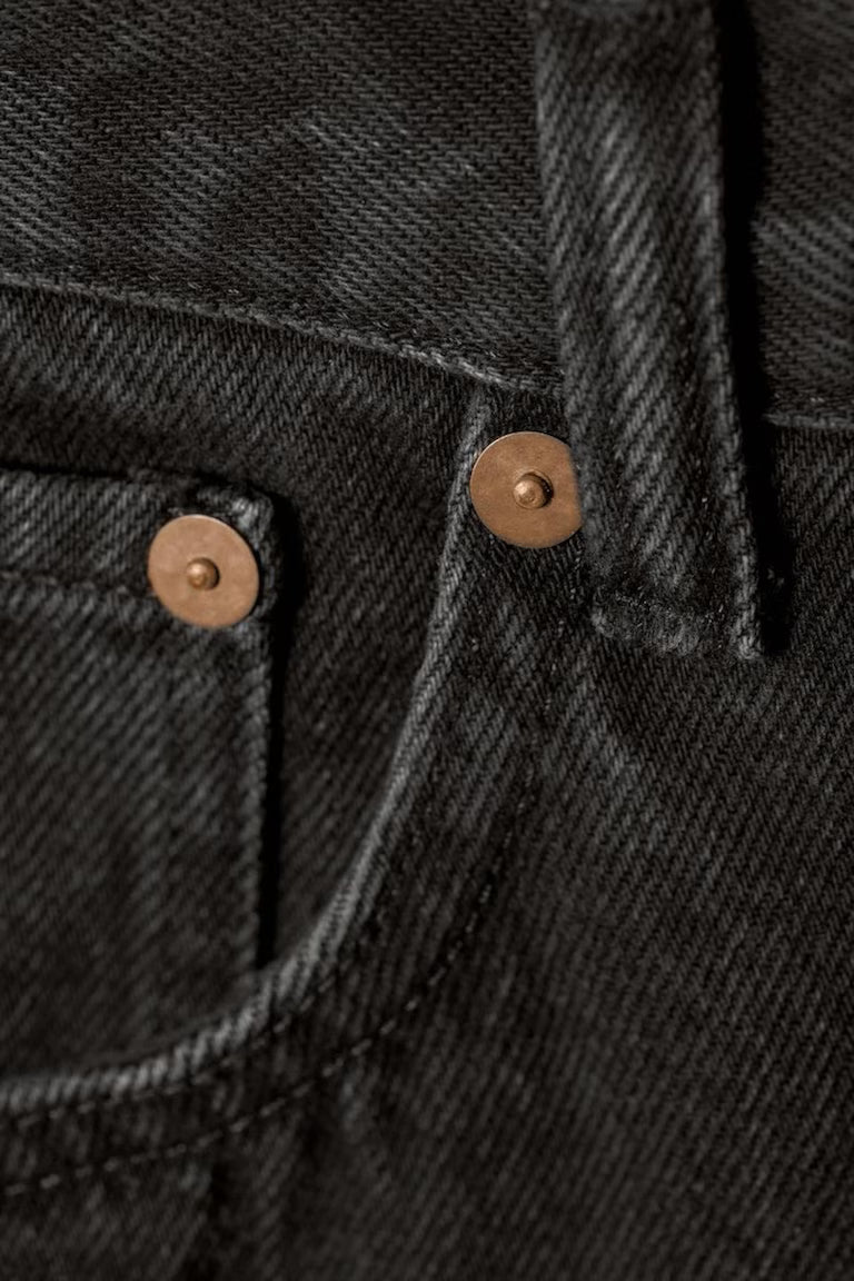 Close-up of black denim fabric with brown buttons