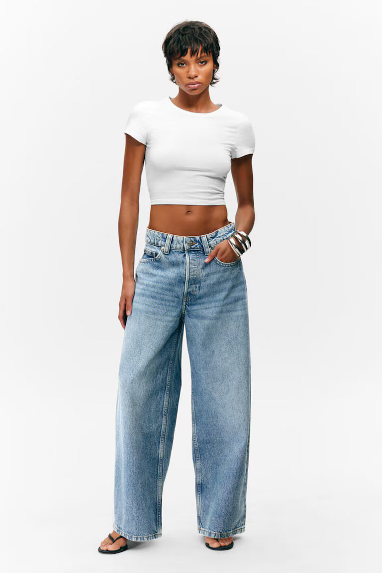 Person wearing a white crop top and blue jeans on a white background
