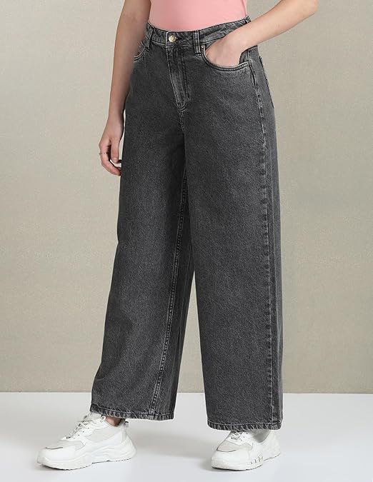 Person wearing black wide-leg jeans with a plain background
