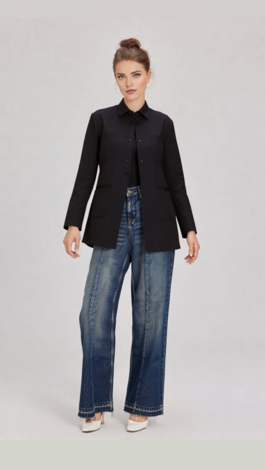 Woman wearing a black jacket and blue jeans on a light gray background